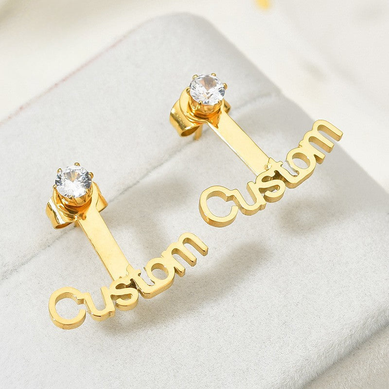 Trendy stainless steel name stud earrings with diamond accents and cut-out letter design.